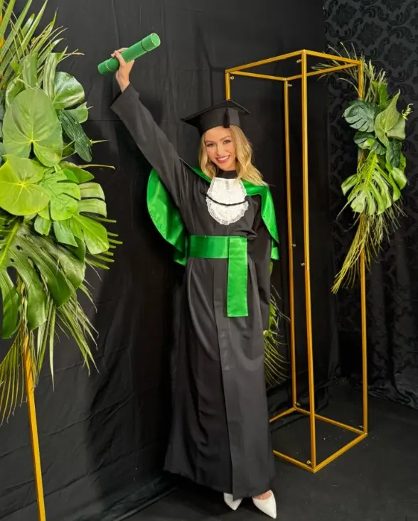 Adelara Armani de beca na formatura em Biomedicina, erguendo o canudo